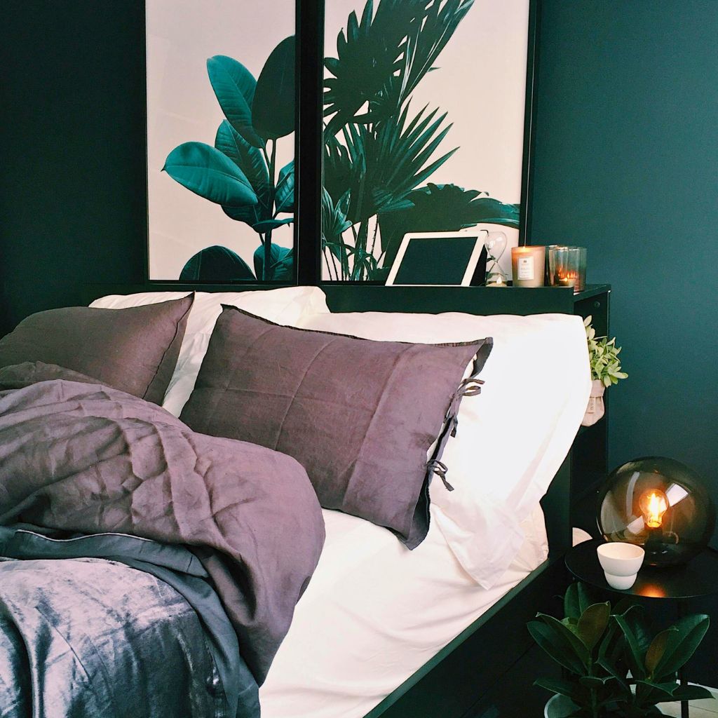 An image of a bed in a green bedroom with some plants